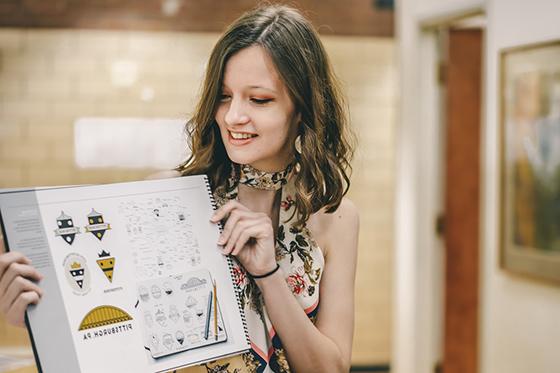 Photo of a female Chatham University student holding up a set of graphics during a presentation